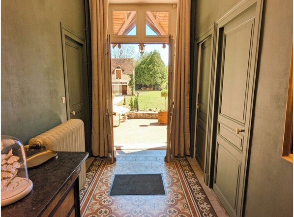 A hallway leading to a door with a view of a house and garden. - Gîte Saint Sauveur en Puisyae (Leugny)