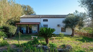 A two-story house with a tiled roof, a small balcony, and a garden with a palm tree and rocks. - House Sogni di Giove With Private Pool (Syracuse)
