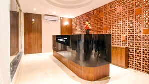 Una recepción con un letrero, un panel de madera y una planta en maceta.