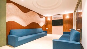 Un interior moderno con un sofá azul, paneles de madera y un televisor de pantalla plana.
