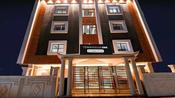 Un edificio de varios pisos con un letrero que dice 'Townhouse Oak' y una entrada protegida por una reja.