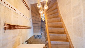Un escalier en bois avec une rampe, un mur orné d’un motif et un luminaire suspendu.