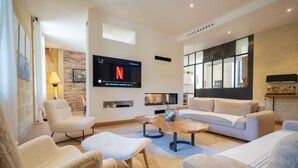 Un salon moderne avec un téléviseur à écran plat, un canapé, une table basse et un fauteuil.