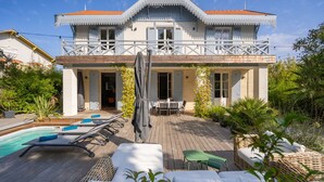 Un bâtiment à deux étages doté d’un balcon, d’une piscine et d’un espace salon extérieur.