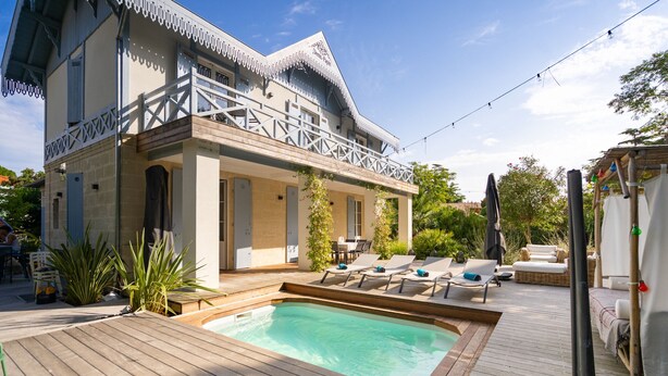 Un espace aménagé au bord de la piscine, avec une terrasse en bois, des chaises longues et une petite piscine.