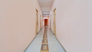A long, narrow hallway with doors on both sides, leading to an open area at the end. - Super Hotel O Anna Nagar Madurai (Madurai)