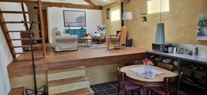 Un vaste espace de vie comprenant un escalier, une table Ă manger et un coin cuisine.
