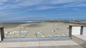 A view of a beach with a parking area and a port in the background. - Beachfront Loft Terrace & Sea View in Zeebrugge (Brugge)