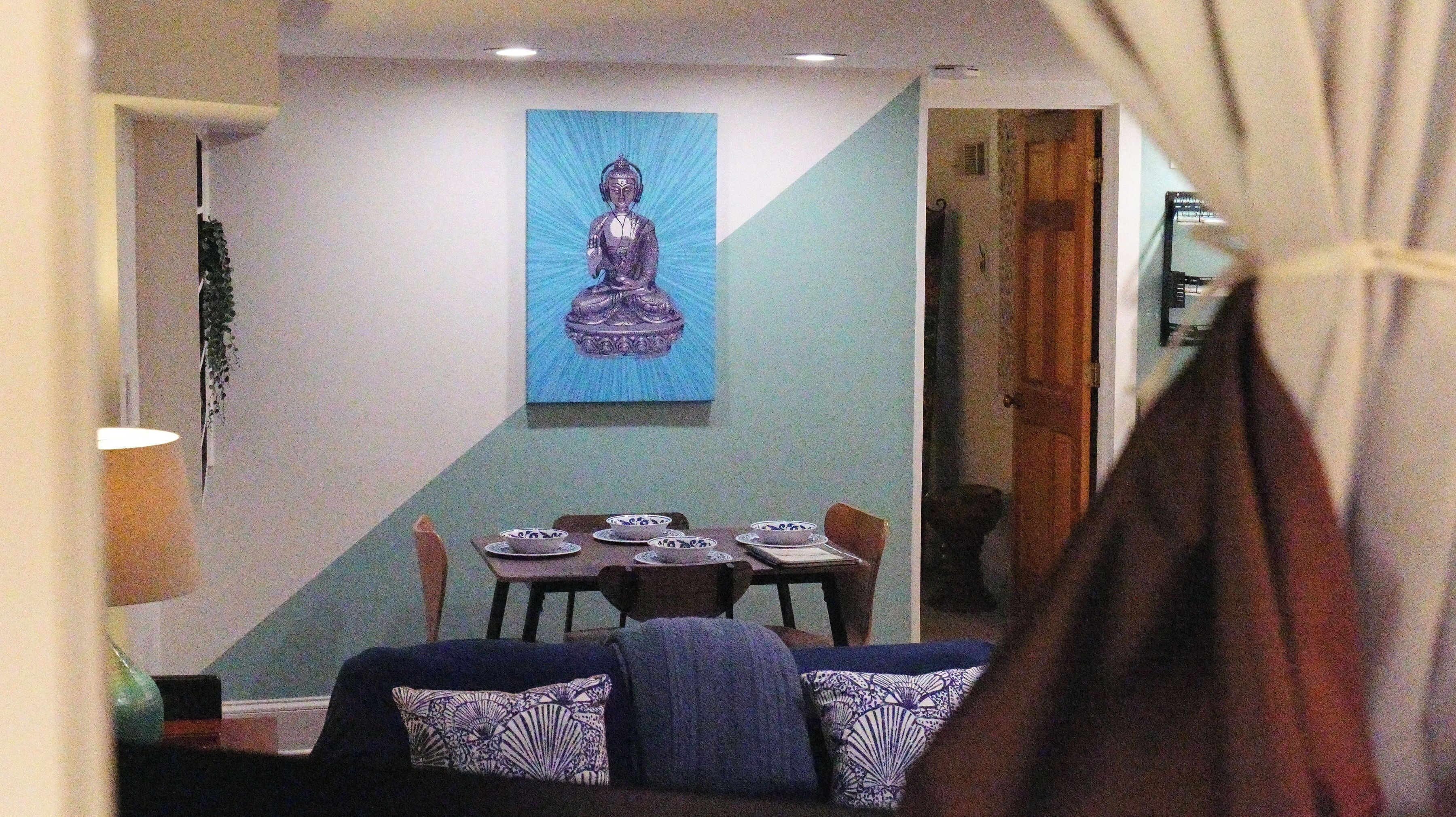 Un comedor con una mesa preparada para cuatro, una pared azul y una estatua de Buda.