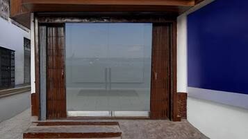 A building entrance with a large glass door, steps leading up to it, and a blue wall to the right.