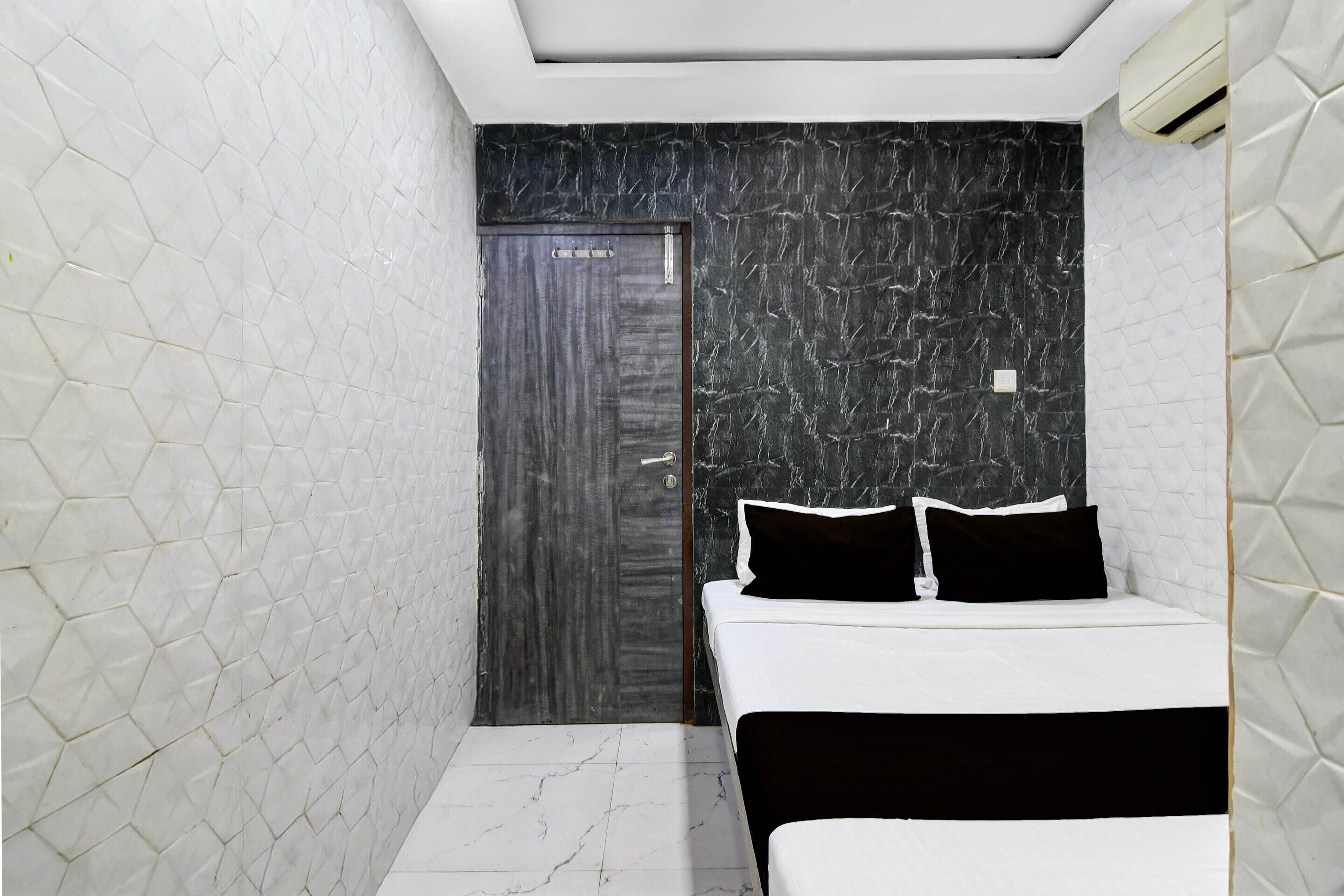 A modern hotel room with a bed, a door, and a wall with a geometric pattern.