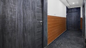 Ein Flur mit dunklen Holztüren, einer Holzwand mit Paneelen und einem Fliesenboden.