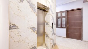 An elevator with marble walls, a wooden door, and a carpeted floor. - Saver Single Hotel Chhillar Inn (New Delhi)