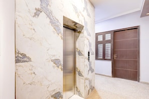 An elevator with marble walls, a wooden door, and a carpeted floor. - Saver Single Hotel Chhillar Inn (New Delhi)