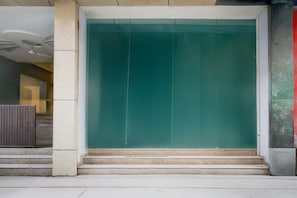 A building entrance with a green door, steps leading up to it, and a concrete pillar to the left. - Saver Single Hotel Chhillar Inn (New Delhi)