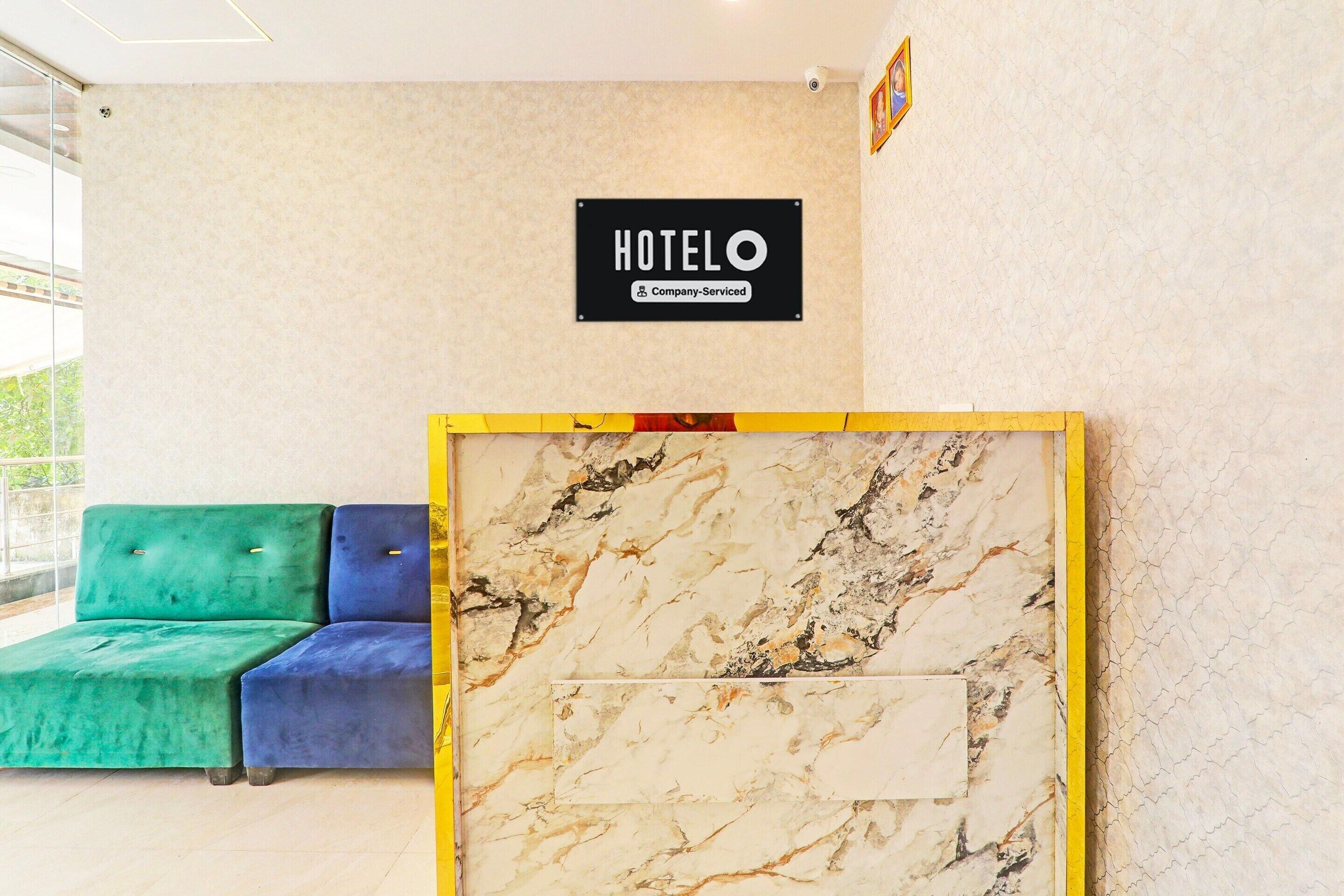 A hotel reception area with a marble reception desk, a green and blue seating area, and a sign that reads 'HOTEL'.