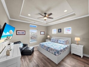 A bedroom with a bed, a ceiling fan, a TV, a window, and a desk. - Heaven's Song 3 Bedroom Home (Port Bolivar)