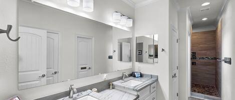 Un baño moderno con dos lavamanos, un espejo grande y una zona de ducha.