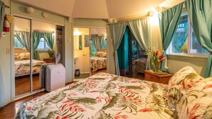 Ein Schlafzimmer mit einem Bett, einem Spiegel, einem Kleiderschrank und einem Fenster mit Vorhängen.