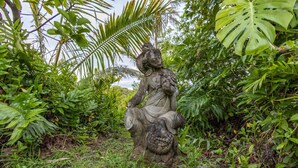 Eine steinerne Statue in üppiger, grüner Umgebung.