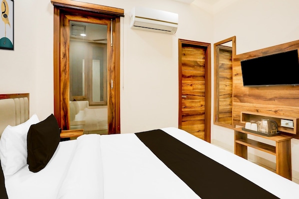 A hotel room with a bed, a television, a wooden wall panel, and a door.