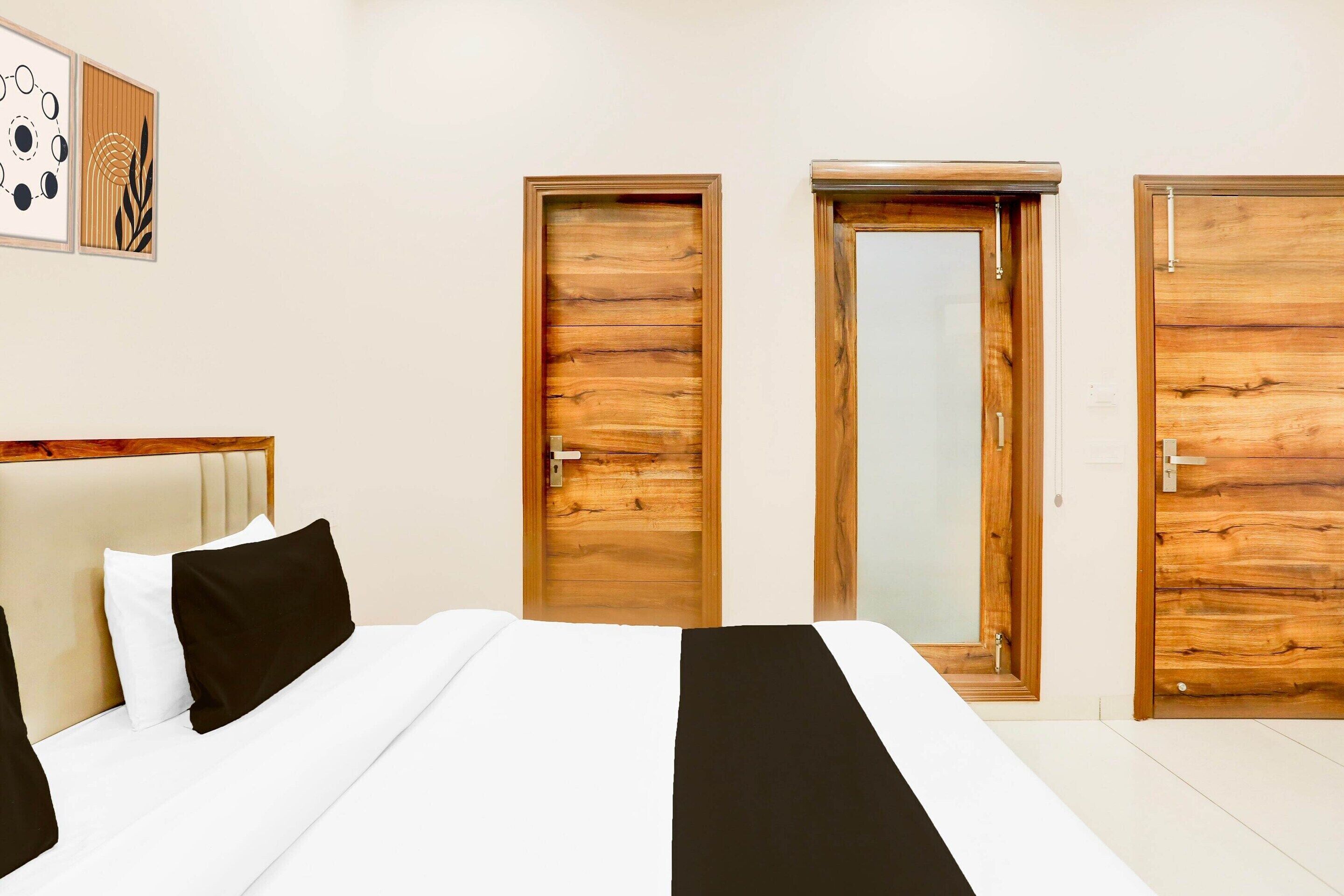 A bedroom with a bed, two wooden doors, and a mirror.