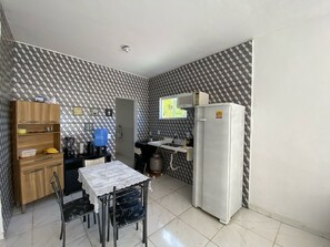 Eine kleine Küche mit Kühlschrank, Kaffeemaschine, Wasserspender und Mikrowelle.
