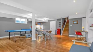 A spacious living area with a ping pong table, a dining table, and a staircase leading to an upper level. - 2 Bed 2 Bath in Orleans (Ottawa)