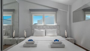 A modern hotel room with a large bed, two bedside tables, a window with a view, and a mirror. - SLV Nefeli Apartment (Pangaio)