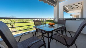 A balcony with a table and chairs, a laptop, and a bowl of fruit. - SLV Nefeli Apartment (Pangaio)