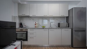 A modern kitchen with white cabinets, a stainless steel refrigerator, a microwave, and a built-in oven. - SLV Nefeli Apartment (Pangaio)
