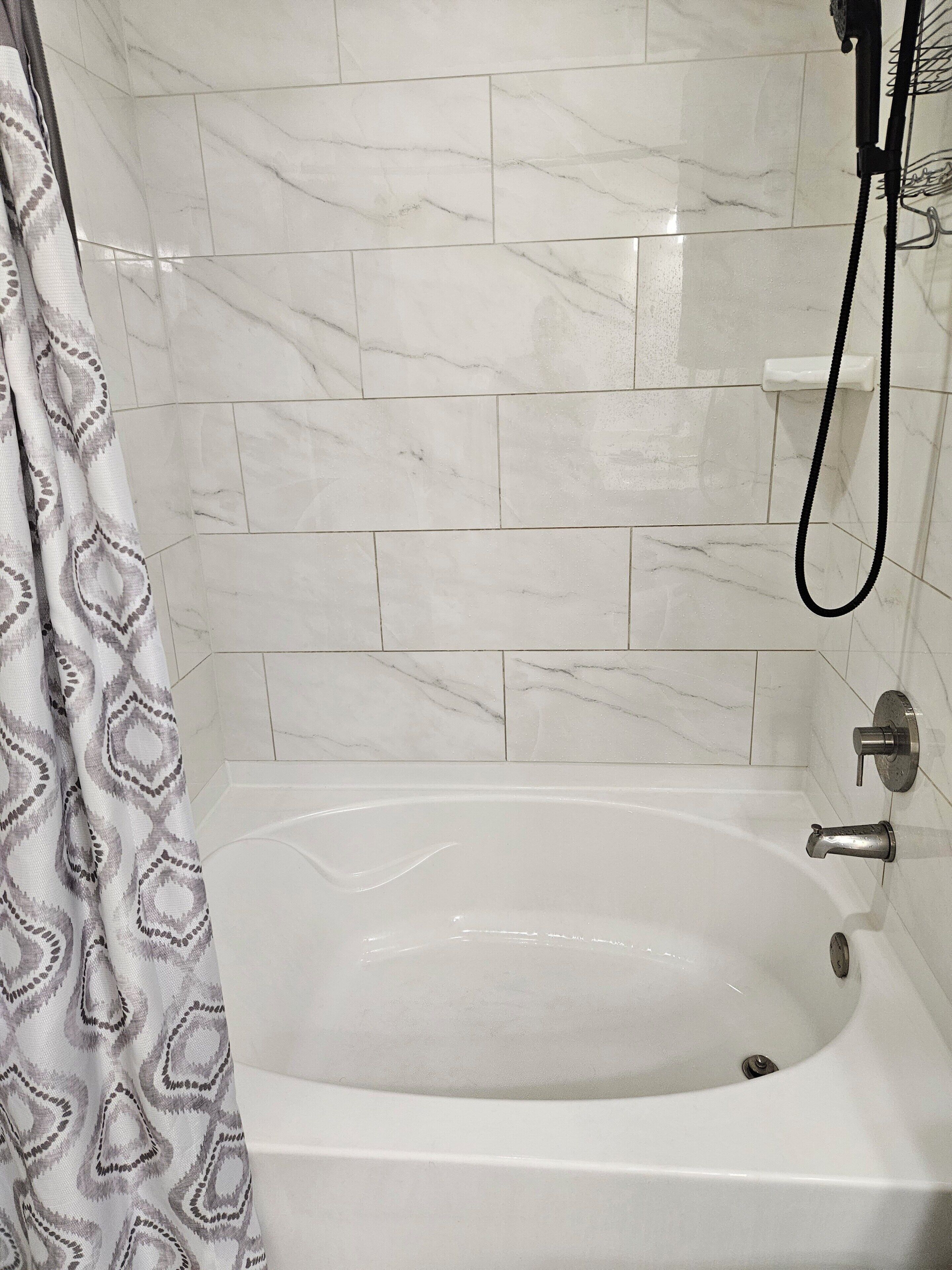 Une salle de bain avec une baignoire, une douche et des murs carrelés.