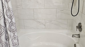 A bathroom with a bathtub, shower, and tiled walls.