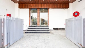 A building entrance with a wooden ceiling, glass doors, and a red circular object on the wall. - Classic With Balcony Surajpur Greater Noida (Greater Noida)