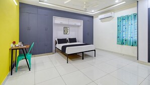 Un dormitorio con una cama, una mesa con una silla, un equipo de aire acondicionado y un ventilador de techo.