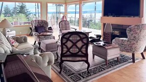 A living room with a fireplace, large windows, and a view of the outdoors. - Epic views, beautiful location, private & quiet (Burien)