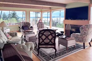 A living room with a fireplace, large windows, and a view of the outdoors. - Epic views, beautiful location, private & quiet (Burien)