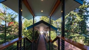 A covered wooden walkway with metal railings, surrounded by trees. - Epic views, beautiful location, private & quiet (Burien)
