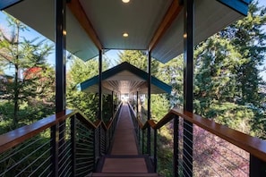 A covered wooden walkway with metal railings, surrounded by trees. - Epic views, beautiful location, private & quiet (Burien)