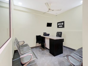 Zona de recepción de hotel con mostrador, sillas, ventilador de techo y señal indicando servicios de la empresa.