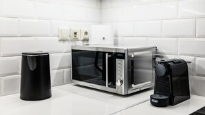 A modern kitchen with a microwave, coffee maker, and trash bin. - MZ Kolonaki Hills (Athina)