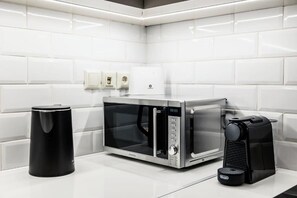 Eine moderne Küche mit Mikrowelle, Kaffeemaschine und Mülleimer.