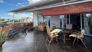 A rooftop terrace with a covered seating area, a table, and chairs. - Penthouse 3 min walk from Flic en Flac beach (Flic en Flac)