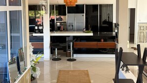 A modern kitchen with a central island, bar stools, a dining table, and a hanging light fixture. - Penthouse 3 min walk from Flic en Flac beach (Flic en Flac)