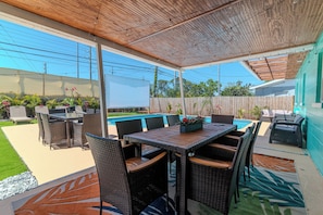 Eine Terrasse im Freien mit Pool, Korbmöbeln und Blick auf den Garten.