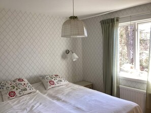 A bedroom with a bed, a bedside lamp, a window with curtains, and a wall with a diamond pattern. - 4 Star Holiday Home in Skanes-fagerhult (Skånes Fagerhult)