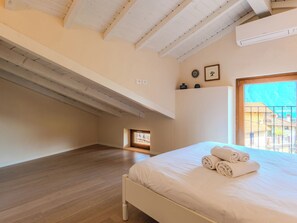 Ein Schlafzimmer mit Holzboden, einem Bett mit weißer Bettwäsche, einem Oberlicht und Blick auf Gebäude.