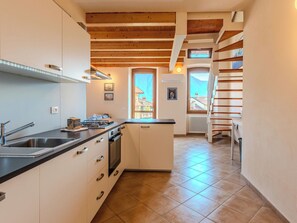 A modern kitchen with a built-in stove, a sink, and a window with a view of buildings. - La Terza Casa by Interhome (Tremezzina)
