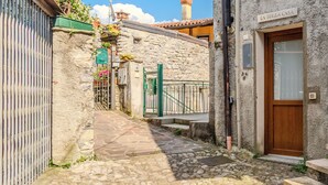 A narrow cobblestone street leading to a stone building with a wooden door and a sign reading 'LA TERZA CASA'. - La Terza Casa by Interhome (Tremezzina)