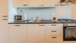 A modern kitchen with white cabinets, a built-in microwave, a gas stove, and a stainless steel range hood. - La Terza Casa by Interhome (Tremezzina)